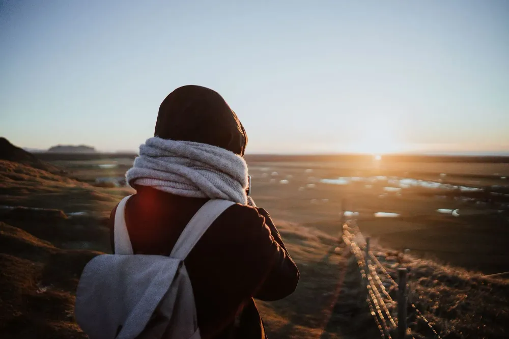 traveler with scarf and backpack at sunset